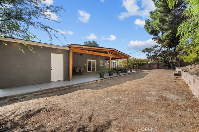 rear view of property with ceiling fan and a patio area