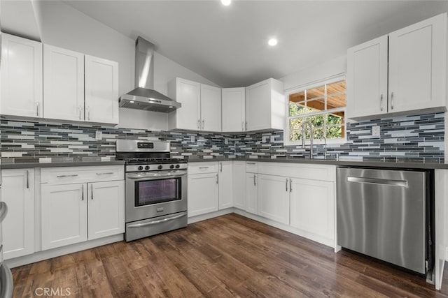 kitchen with white cabinets, dark hardwood / wood-style floors, wall chimney range hood, and appliances with stainless steel finishes