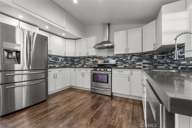 kitchen with white cabinetry, dark wood-type flooring, stainless steel appliances, wall chimney range hood, and tasteful backsplash