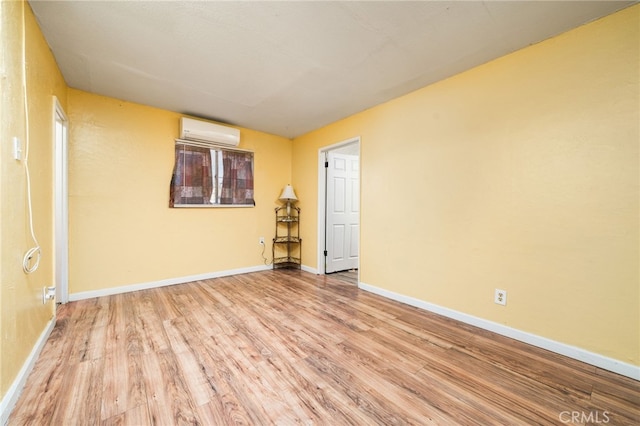 spare room featuring light hardwood / wood-style floors and an AC wall unit