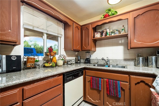 kitchen with light stone counters, white dishwasher, sink, and tasteful backsplash