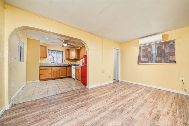 kitchen featuring light wood-type flooring, a textured ceiling, sink, a wall mounted AC, and ceiling fan