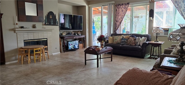 living room featuring a tiled fireplace, plenty of natural light, and light tile patterned flooring