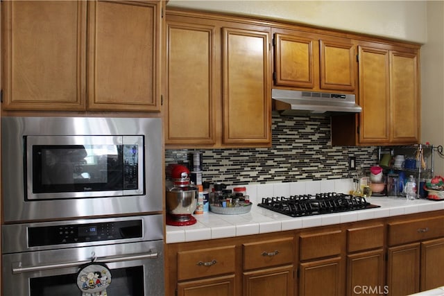 kitchen with decorative backsplash, oven, tile countertops, and black gas stovetop