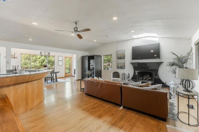 living room with ceiling fan, lofted ceiling, and light wood-type flooring