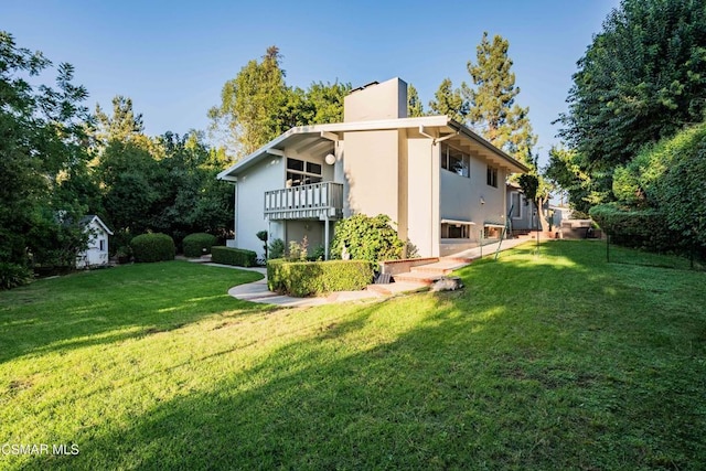 rear view of house featuring a balcony and a lawn