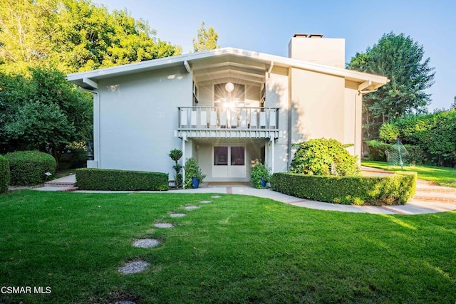 view of front facade featuring a balcony and a front yard