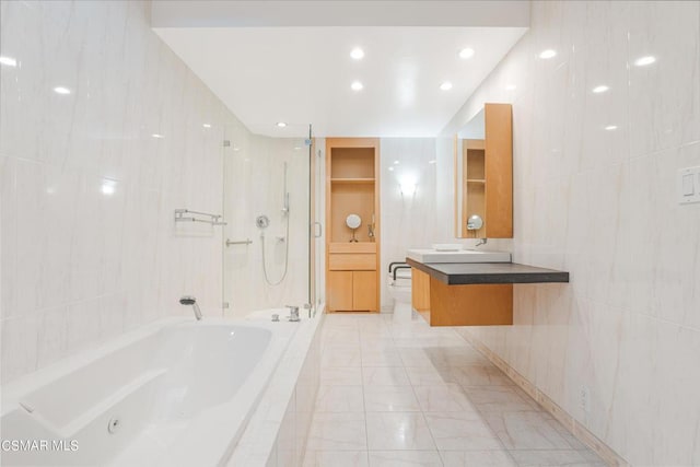 bathroom with tile walls, vanity, and independent shower and bath