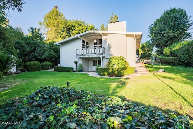 rear view of house with a balcony and a yard