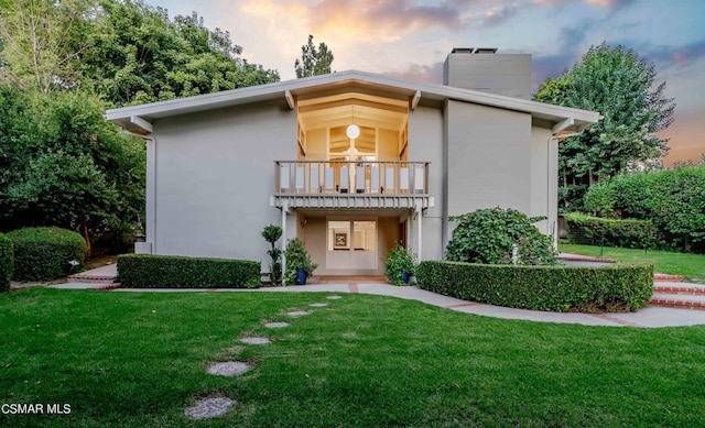 view of front of house with a yard and a balcony