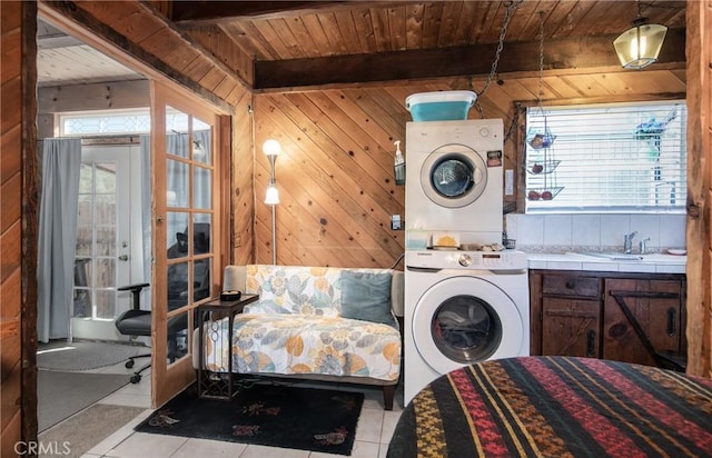 laundry room featuring stacked washer and dryer, plenty of natural light, wooden walls, and wood ceiling