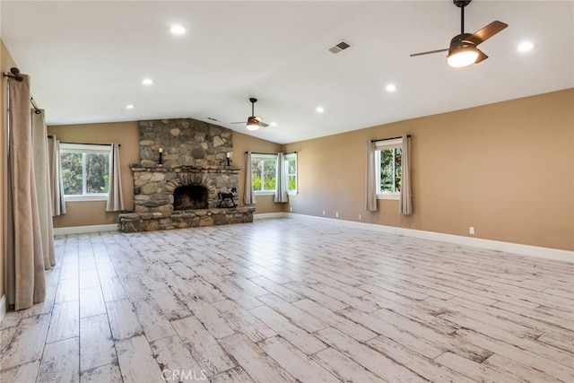 unfurnished living room featuring ceiling fan, a stone fireplace, lofted ceiling, and light hardwood / wood-style floors