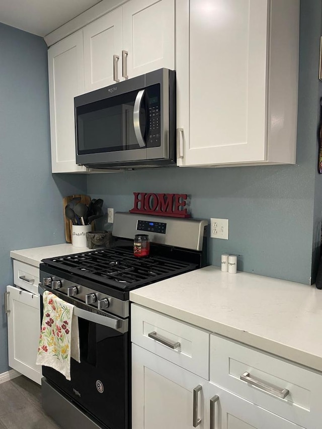 kitchen with white cabinetry, dark hardwood / wood-style floors, and appliances with stainless steel finishes