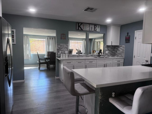 kitchen with white cabinets, stainless steel fridge, dark hardwood / wood-style flooring, and plenty of natural light