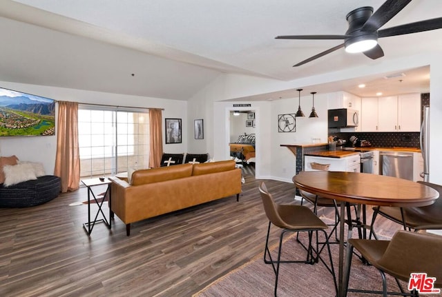 dining area with dark hardwood / wood-style flooring, vaulted ceiling, and ceiling fan