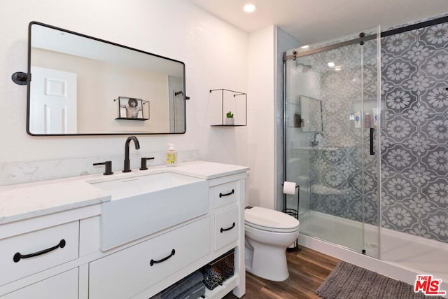 bathroom featuring toilet, vanity, a shower with door, and hardwood / wood-style flooring