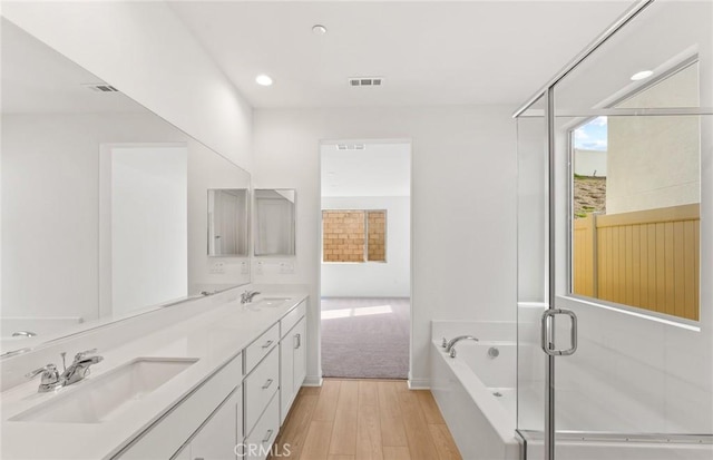 bathroom featuring shower with separate bathtub, wood-type flooring, and vanity