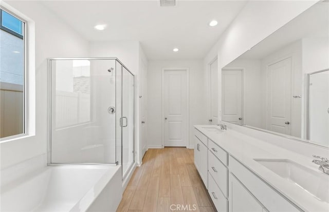 bathroom featuring hardwood / wood-style flooring, plus walk in shower, and vanity