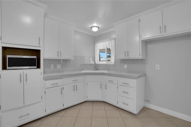 kitchen with light countertops, stainless steel microwave, a sink, and white cabinets