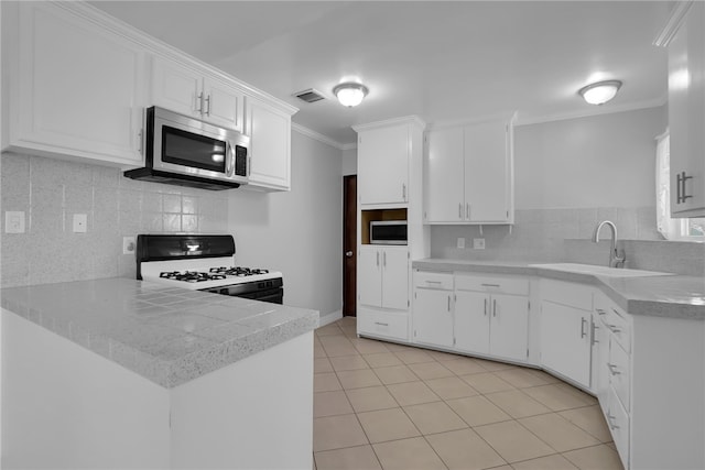 kitchen with light tile patterned floors, white cabinetry, gas range, crown molding, and sink