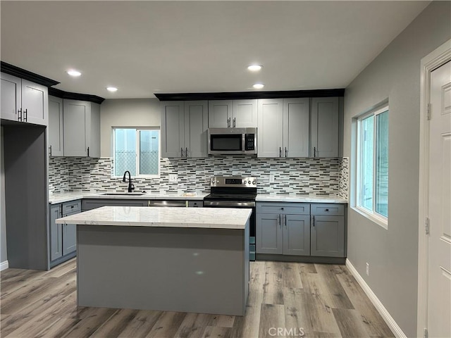 kitchen featuring a wealth of natural light, light hardwood / wood-style floors, sink, and appliances with stainless steel finishes