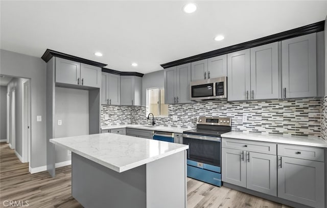 kitchen featuring gray cabinets, a kitchen island, stainless steel appliances, and light wood-type flooring