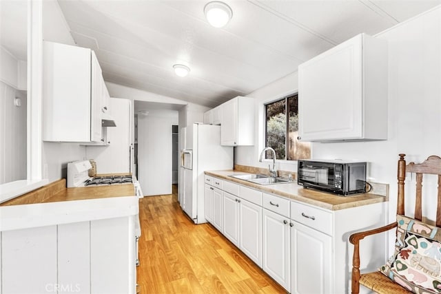 kitchen with light hardwood / wood-style floors, sink, white refrigerator with ice dispenser, white cabinets, and range