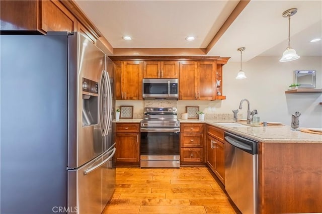 kitchen with kitchen peninsula, light stone countertops, stainless steel appliances, decorative light fixtures, and light hardwood / wood-style floors