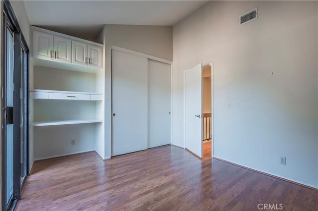 unfurnished bedroom with hardwood / wood-style floors and high vaulted ceiling