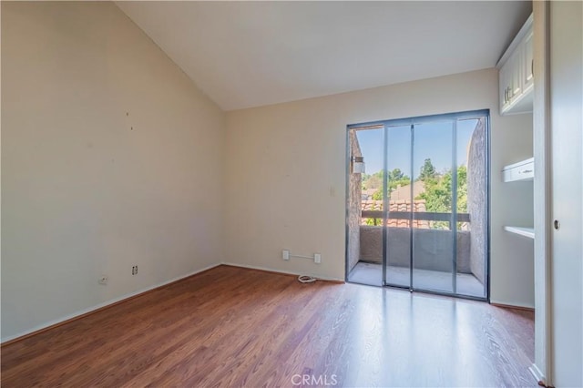 empty room with hardwood / wood-style flooring and vaulted ceiling