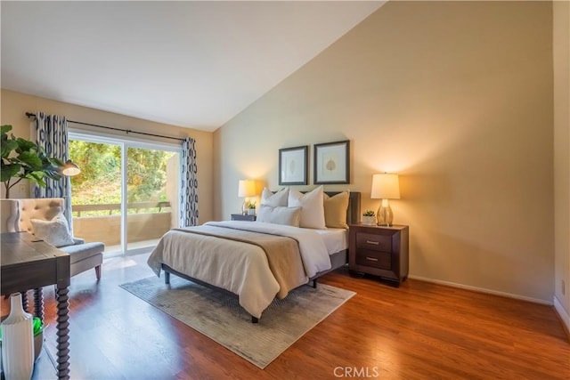 bedroom featuring access to exterior, hardwood / wood-style floors, and high vaulted ceiling