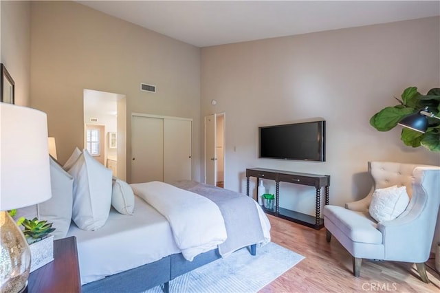 bedroom featuring light hardwood / wood-style flooring, a high ceiling, and a closet