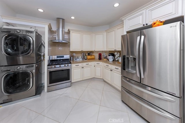 kitchen featuring light tile patterned flooring, tasteful backsplash, stainless steel appliances, stacked washer / dryer, and wall chimney range hood