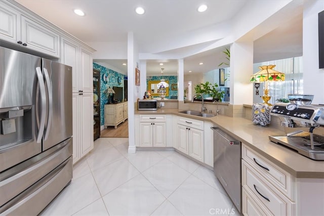 kitchen featuring appliances with stainless steel finishes, sink, kitchen peninsula, and white cabinetry