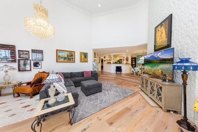 living room featuring a high ceiling, ornamental molding, hardwood / wood-style floors, and a notable chandelier