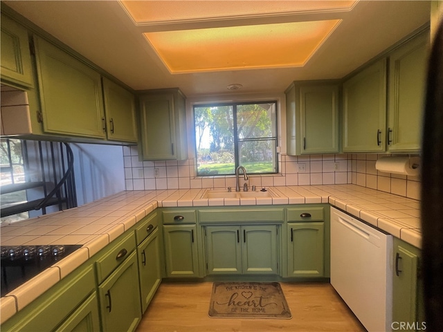 kitchen featuring tile counters, light hardwood / wood-style floors, sink, and green cabinets