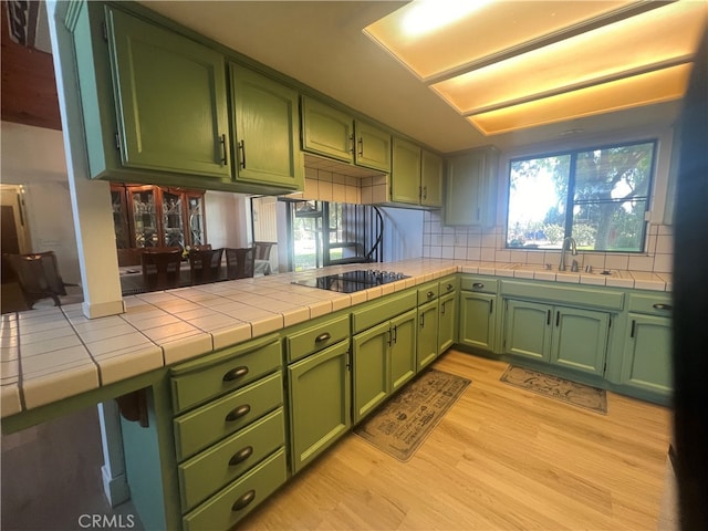 kitchen featuring green cabinetry, light hardwood / wood-style floors, tile counters, and a wealth of natural light