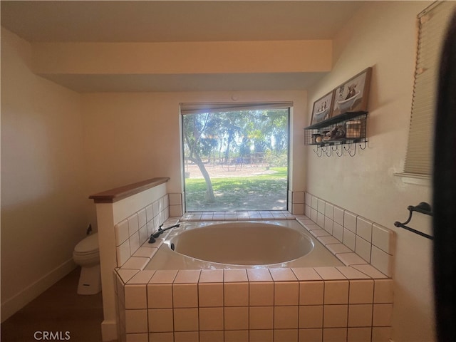 bathroom featuring tiled bath and toilet