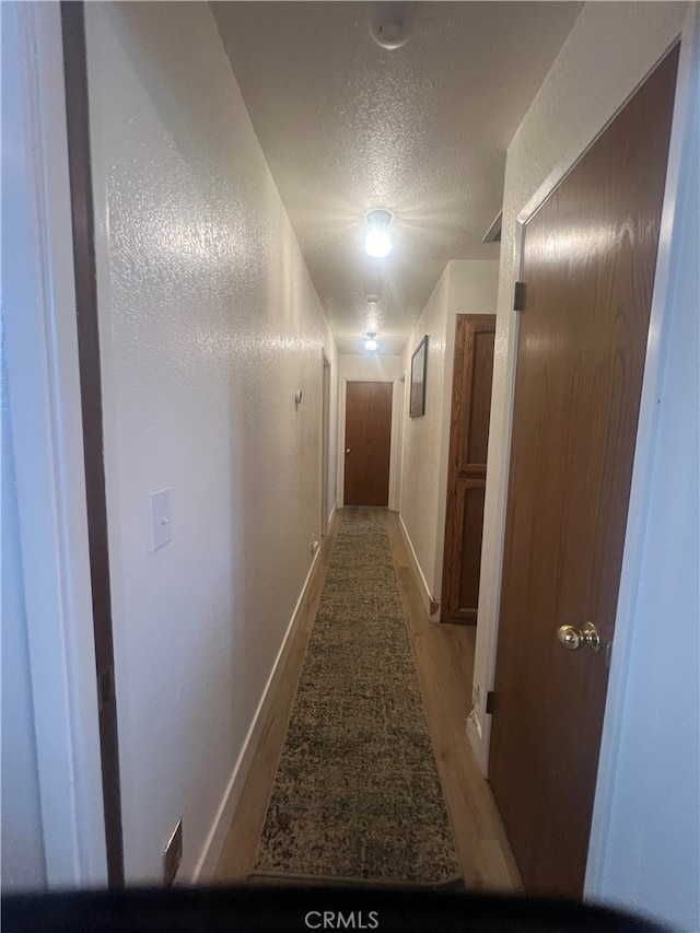 corridor featuring a textured ceiling and light hardwood / wood-style flooring