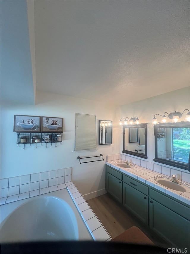 bathroom featuring vanity, a textured ceiling, hardwood / wood-style flooring, and a tub