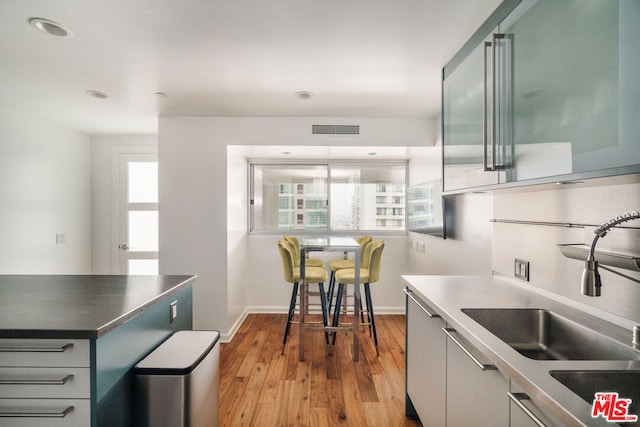 kitchen with white cabinets, light hardwood / wood-style floors, a healthy amount of sunlight, and sink