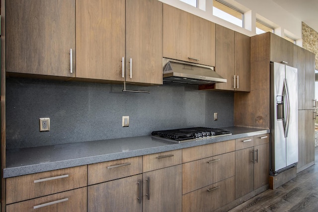 kitchen with backsplash, appliances with stainless steel finishes, and dark hardwood / wood-style floors