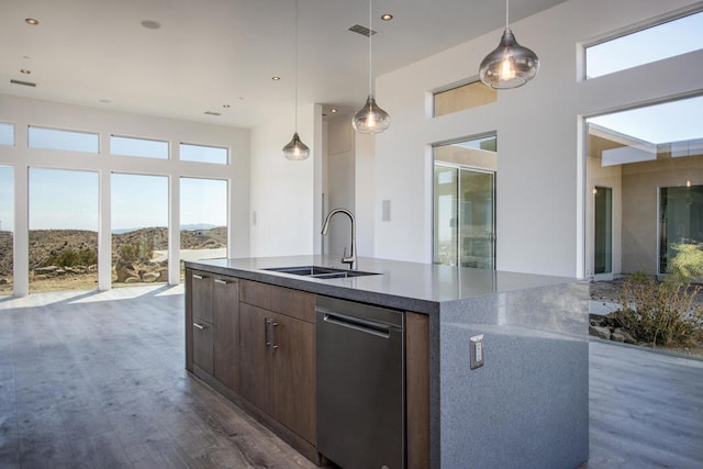 kitchen featuring a mountain view, an island with sink, sink, decorative light fixtures, and dark wood-type flooring