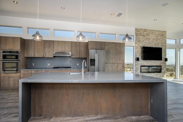 kitchen featuring decorative backsplash, dark wood-type flooring, pendant lighting, stainless steel appliances, and sink