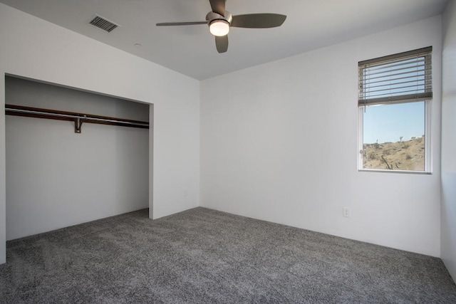 unfurnished bedroom with ceiling fan, dark carpet, and a closet