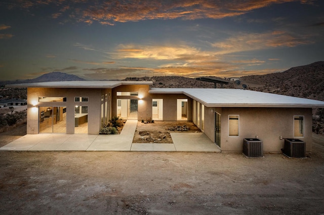 view of front of house featuring a mountain view, central AC unit, and a patio area