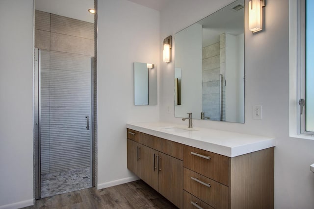 bathroom with wood-type flooring, vanity, and a shower with door