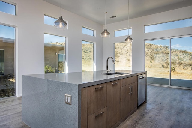 kitchen featuring pendant lighting, sink, dark wood-type flooring, and an island with sink