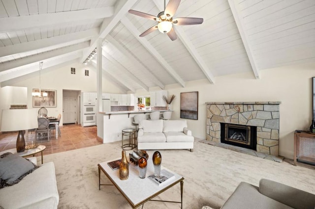 living room with beam ceiling, a stone fireplace, high vaulted ceiling, light tile patterned flooring, and ceiling fan with notable chandelier