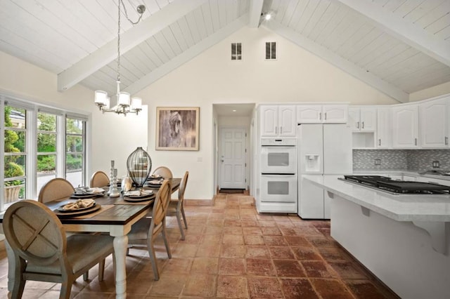 kitchen featuring beamed ceiling, white cabinets, pendant lighting, and white appliances